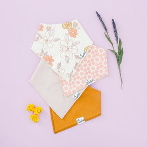 Copper Pearl Bandana Bibs in Ferra laying on a purple background